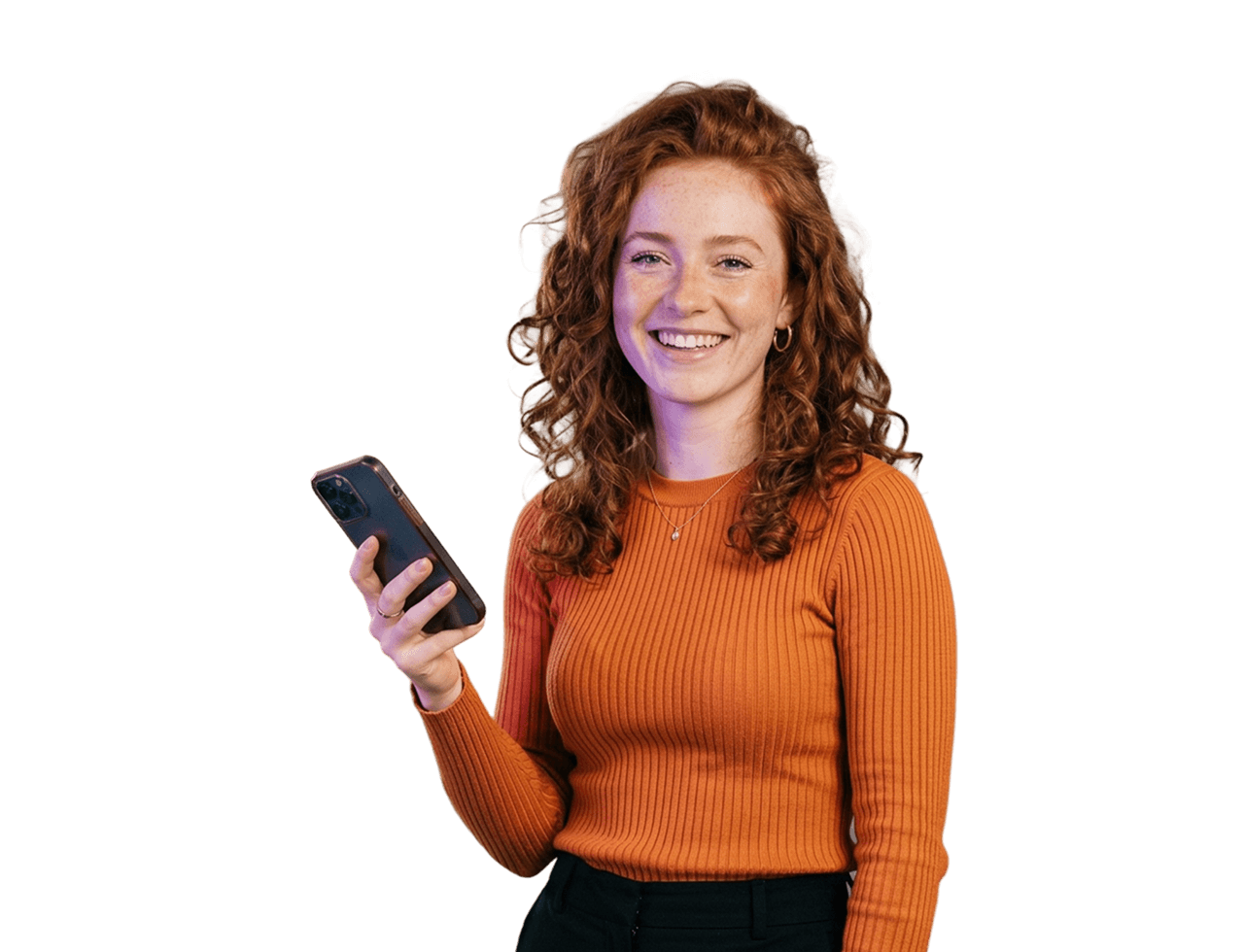 Fiatal vöröshajú nő mobiltelefonnal a kezében mosolyog.